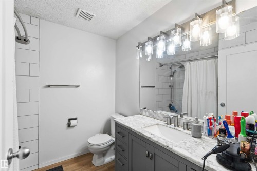 Bathroom featuring a grey vanity with a white countertop, undermount sink, and brushed nickel faucet - 8819 29 Avenue, Edmonton, AB 