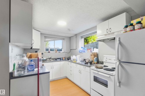 Kitchen featuring white cabinetry, gray countertops, a double basin sink, white electric range, and a white refrigerator - 8819 29 Avenue, Edmonton, AB 