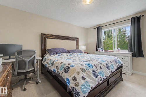 Carpeted interior room featuring a large window, a ceiling-mounted light fixture, and neutral wall paint - 25 12004 22 Avenue, Edmonton, AB - Indoor Photo Showing Bedroom