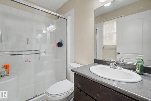 Bathroom featuring a vanity with an integrated sink, dark countertop, and a large mirror - 25 12004 22 Avenue, Edmonton, AB - Indoor Photo Showing Bathroom
