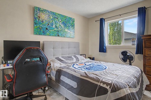 Bedroom featuring a window with blue drapes, neutral wall paint, and carpet flooring - 25 12004 22 Avenue, Edmonton, AB - Indoor Photo Showing Bedroom