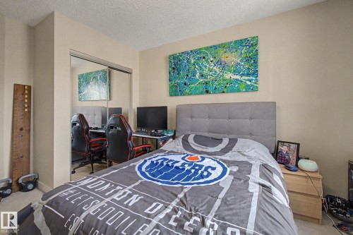 Bedroom featuring a tufted upholstered headboard, mirrored closet doors, and neutral wall paint - 25 12004 22 Avenue, Edmonton, AB - Indoor Photo Showing Bedroom