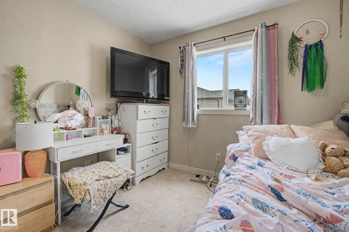 Neutral wall paint, light-colored carpeting, and a window with white trim - 25 12004 22 Avenue, Edmonton, AB - Indoor Photo Showing Bedroom