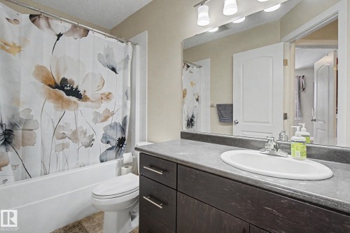 Bathroom featuring a dark wood-finish vanity with a gray countertop, an integrated sink, and an overhead vanity light fixture - 25 12004 22 Avenue, Edmonton, AB - Indoor Photo Showing Bathroom
