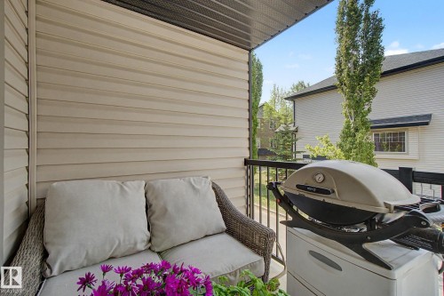 Covered outdoor balcony featuring tan siding and black railings - 25 12004 22 Avenue, Edmonton, AB - Outdoor With Exterior