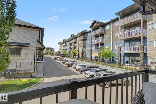Exterior balcony with black railing overlooking a paved parking area - 25 12004 22 Avenue, Edmonton, AB - Outdoor With Balcony