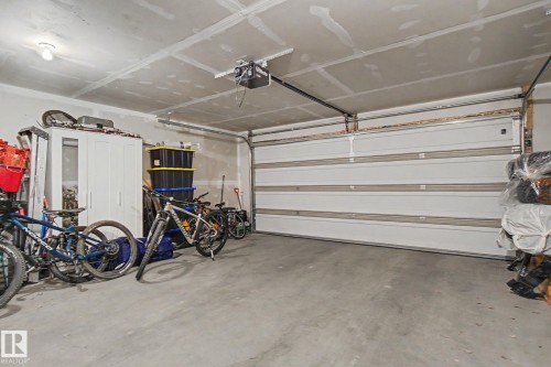 Spacious garage featuring a concrete floor, overhead lighting, and an automatic garage door opener - 25 12004 22 Avenue, Edmonton, AB - Indoor Photo Showing Garage