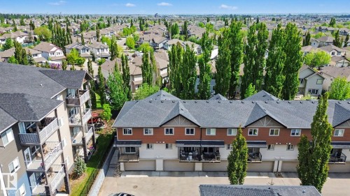 Townhome complex featuring brick and siding exteriors, private balconies, individual garages, and a paved parking area - 25 12004 22 Avenue, Edmonton, AB - Outdoor With Facade