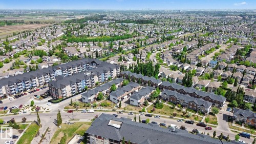 Aerial perspective showcasing a residential neighborhood with a mix of multi-story apartment buildings and single-family homes - 25 12004 22 Avenue, Edmonton, AB - Outdoor With View