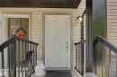 Entryway with a white paneled door, light beige siding, and black metal railings - 25 12004 22 Avenue, Edmonton, AB  - Outdoor With Exterior 