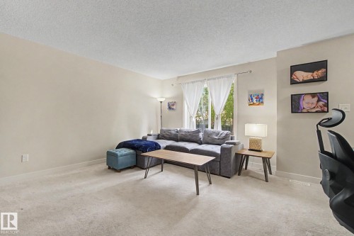 Carpeted interior space featuring light-colored walls and a window with white drapes - 25 12004 22 Avenue, Edmonton, AB - Indoor Photo Showing Living Room