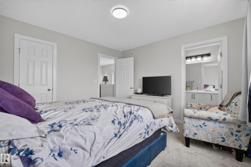 Carpeted bedroom with light gray walls, a flush-mount ceiling light, and white paneled doors - 5129 Lark Crescent, Edmonton, AB 