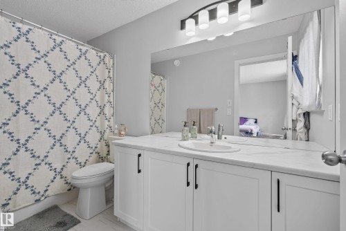 Bathroom featuring a white vanity with panel cabinetry, a single undermount sink, and a spacious countertop - 5129 Lark Crescent, Edmonton, AB 