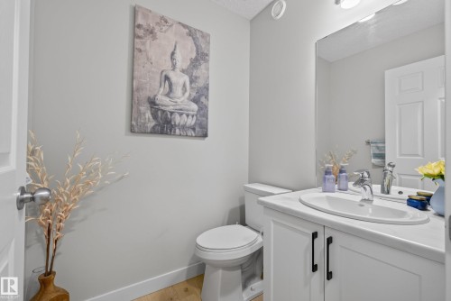 Powder room featuring a white single vanity with an integrated sink, chrome faucet, and white shaker-style cabinetry with black pulls - 5129 Lark Crescent, Edmonton, AB 