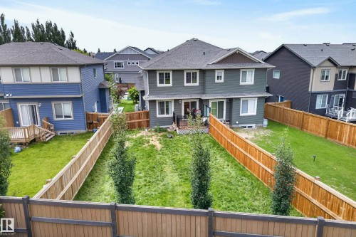 Rear exterior featuring a spacious fenced yard, a rear deck, and a second-story balcony - 5129 Lark Crescent, Edmonton, AB 