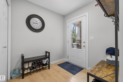 Entryway with wood-finish flooring, a white paneled door with frosted glass insert, and a closet with a white paneled door - 5129 Lark Crescent, Edmonton, AB 