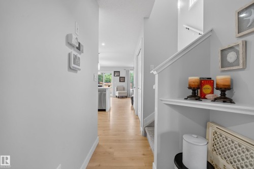 Bright hallway featuring light wood-finish flooring, white baseboards, and neutral wall paint - 5129 Lark Crescent, Edmonton, AB 