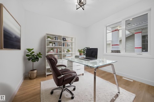 Bright office space featuring light wood-finish flooring, white walls, and a large window with white trim - 803 30 Avenue, Edmonton, AB 