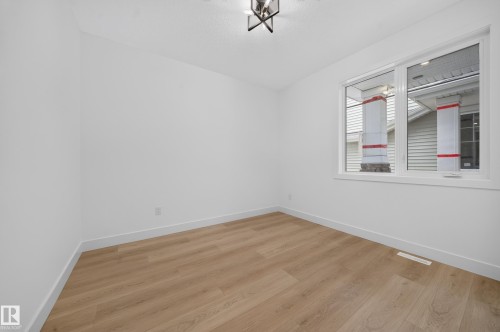 Bright room featuring light wood-finish flooring, white walls, and a contemporary ceiling light fixture - 803 30 Avenue, Edmonton, AB 