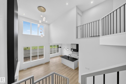 Two-story living area with high ceilings, multiple large windows, and contemporary wood-finish flooring - 803 30 Avenue, Edmonton, AB 