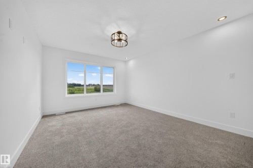 Bright interior space featuring a multi-pane window, flush-mount ceiling fixture, recessed lighting, white baseboards, and neutral-toned carpeting - 803 30 Avenue, Edmonton, AB 
