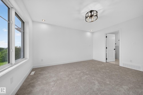 Bright room featuring a large window, neutral carpet, white walls, and a contemporary ceiling fixture - 803 30 Avenue, Edmonton, AB 