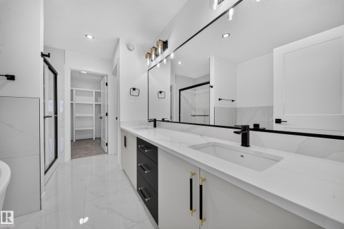 Bathroom featuring a double vanity with white countertops, integrated sinks, and matte black faucets - 803 30 Avenue, Edmonton, AB 