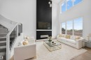 Two-story living area featuring a dramatic fireplace with a black accent wall, an integrated linear electric fireplace, and a wall-mounted television - 803 30 Avenue, Edmonton, AB 