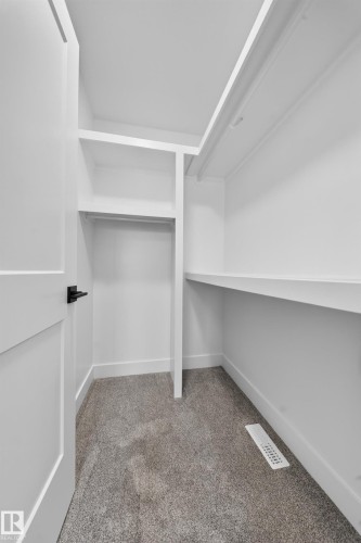 Walk-in closet featuring built-in shelving, hanging rods, light gray carpeting, crisp white walls, and white trim - 803 30 Avenue, Edmonton, AB 