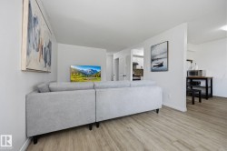 Open-concept living area featuring wood-finish flooring and white walls - 