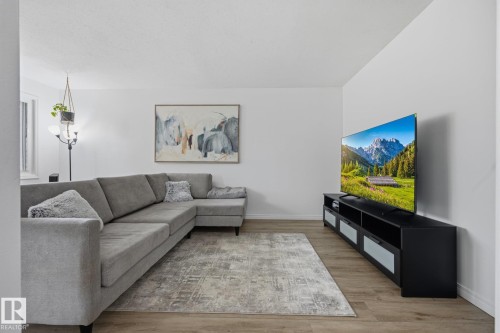 Open concept living area featuring wood-finish flooring and light-toned walls - 105 16428 109 Street, Edmonton, AB 