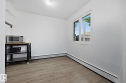 Bright room featuring wood-finish flooring, white walls, and a window with a white frame - 