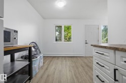 Entry area featuring wood-finish flooring, white walls, and a white paneled door with a sidelight - 