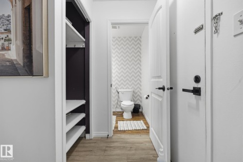 Powder room featuring chevron-patterned wallpaper and wood-finish flooring - 105 16428 109 Street, Edmonton, AB 