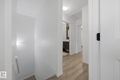 Hallway featuring wood-finish flooring, white painted walls, and ceiling-mounted lighting - 105 16428 109 Street, Edmonton, AB 