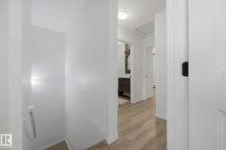 Hallway featuring wood-finish flooring, white painted walls, and ceiling-mounted lighting - 