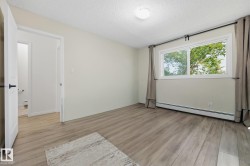 Spacious room featuring wood-finish flooring, a large window with white trim, and light-colored walls - 