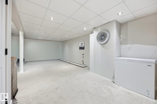 Spacious interior room featuring light-colored carpeting, recessed lighting, and a drop ceiling - 105 16428 109 Street, Edmonton, AB 