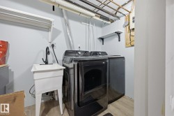 Dedicated laundry area featuring a utility sink with a matte black faucet, light wood-finish flooring, and wall-mounted shelving - 