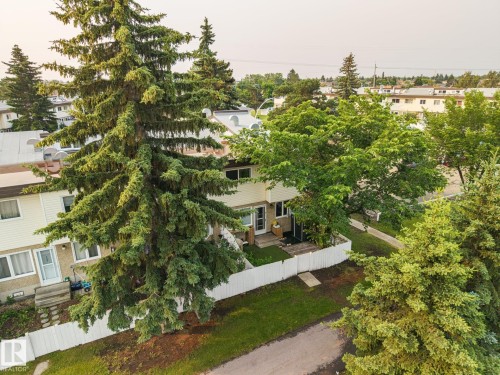Townhome exterior with light-colored siding and a white picket fence - 105 16428 109 Street, Edmonton, AB 