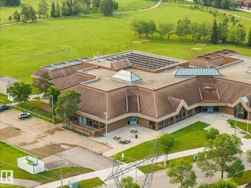 Expansive building featuring a brown shingle roof, multiple skylights, and brick exterior - 105 16428 109 Street, Edmonton, AB 