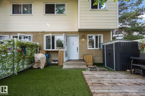Rear exterior featuring a wood deck, artificial turf, and a storage shed - 105 16428 109 Street, Edmonton, AB 