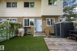 Rear exterior featuring a wood deck, artificial turf, and a storage shed - 