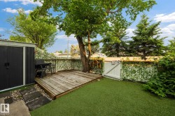 Backyard featuring a wood-finish deck, artificial turf, stepping stones, and a storage shed - 