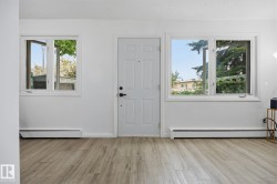 Entryway featuring wood-finish flooring, a paneled door, and two casement windows with white trim - 