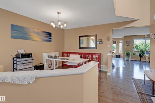 Dining area featuring a contemporary chandelier, wood-finish flooring, and a half-wall partition - 1216 37C Avenue Nw, Edmonton, AB - Indoor