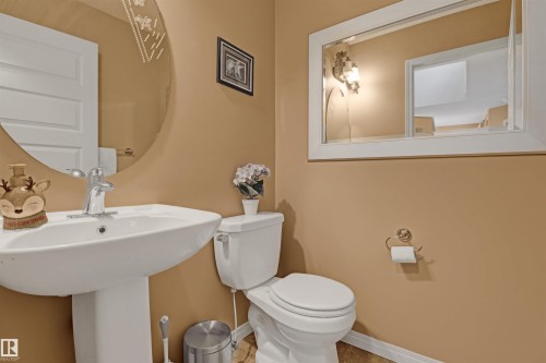 Pedestal sink with chrome faucet, toilet, and decorative wall mirror - 1216 37C Avenue Nw, Edmonton, AB - Indoor Photo Showing Bathroom