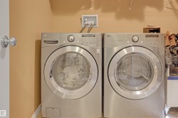 Dedicated laundry area featuring a front-loading washing machine and dryer, overhead shelving, and a wall-mounted utility box - 