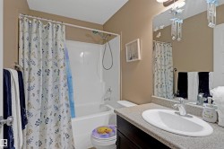 Bathroom featuring a white porcelain tub/shower combination, a vanity with a dark wood-finish cabinet, a light-colored countertop, and an integrated white oval sink - 
