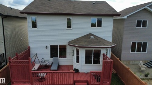 Rear elevation featuring light-colored siding, a multi-level red-stained deck, and a hexagonal sunroom with a shingled roof - 1216 37C Avenue Nw, Edmonton, AB - Outdoor With Exterior